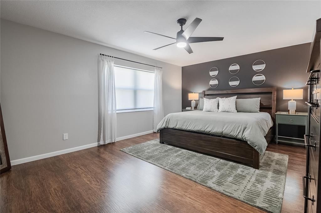 Primary bedroom with Luxury Plank Vinyl and ceiling fan.