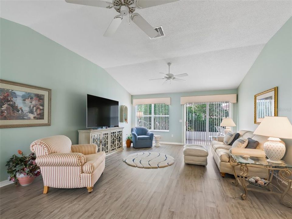 Living Room featuring Vaulted Ceilings, Newer Luxury Vinyl Plank Flooring and Sling Glass Doors leading out to the Lanai.