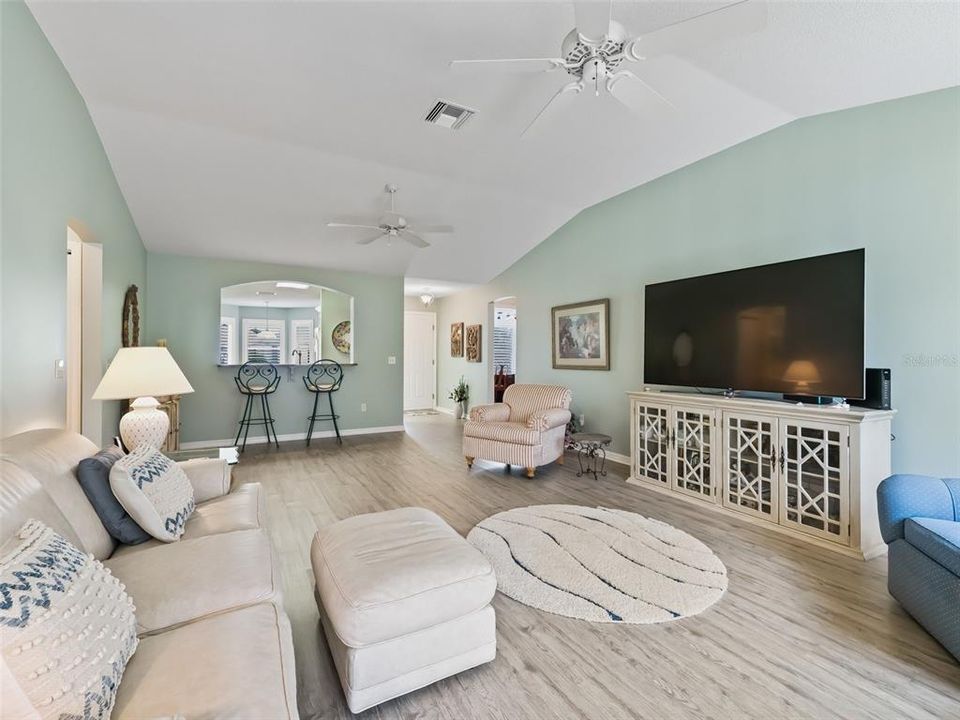 Living Room featuring Vaulted Ceilings, Newer Luxury Vinyl Plank Flooring and Sling Glass Doors leading out to the Lanai