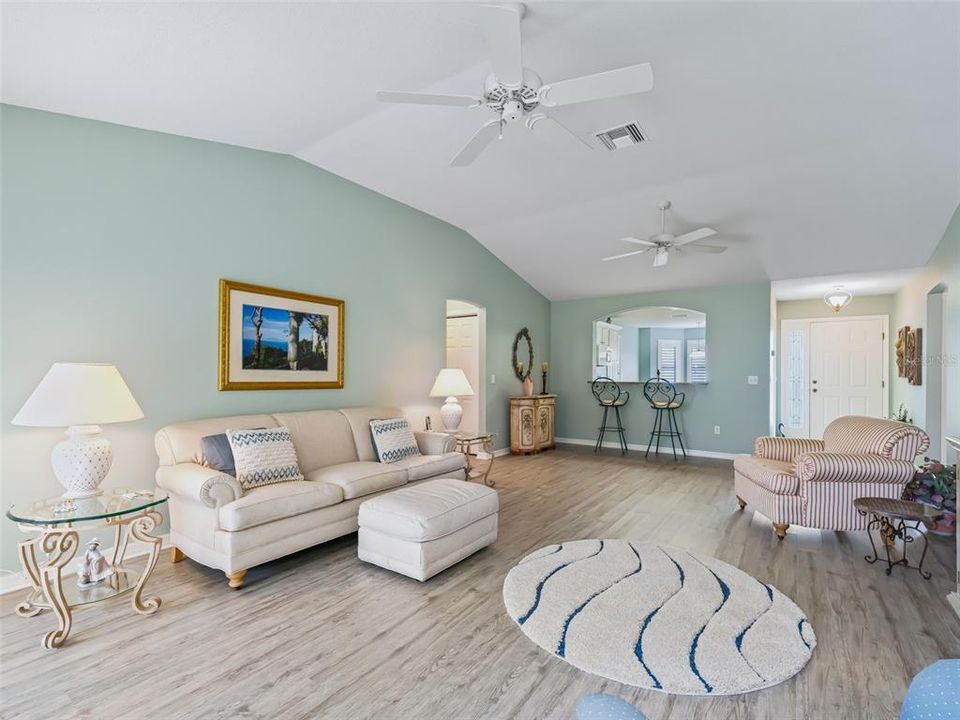 Living Room featuring Vaulted Ceilings, Newer Luxury Vinyl Plank Flooring and Sling Glass Doors leading out to the Lanai