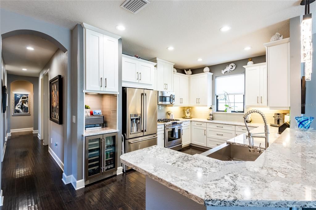 Kitchen with beverage center and beautiful arched hallway that leads to den, secondary bedrooms and separate office