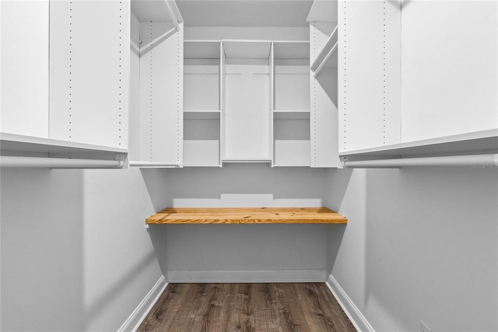 Primary bedroom walk-in closet with custom built-in shelving