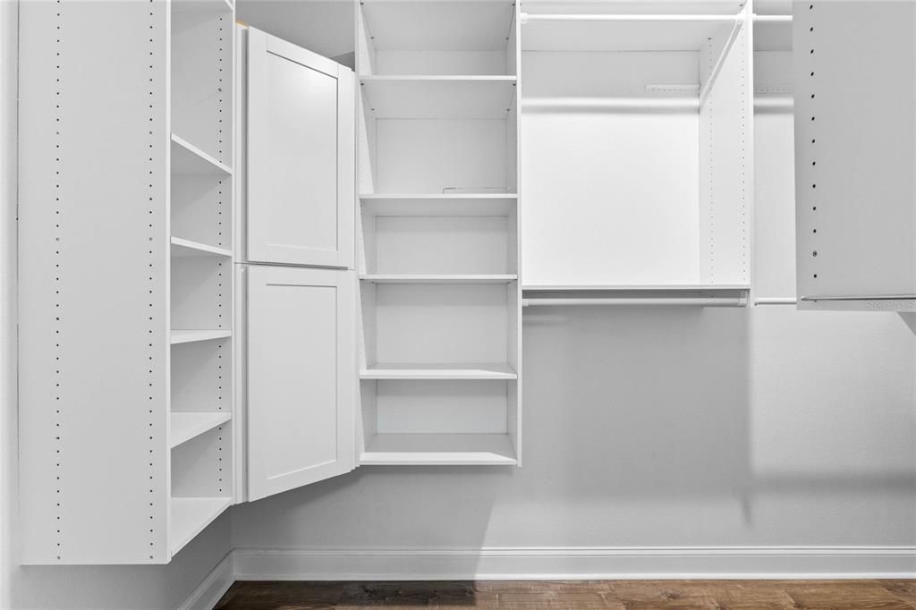Primary bedroom walk-in closet with custom built-in shelving.