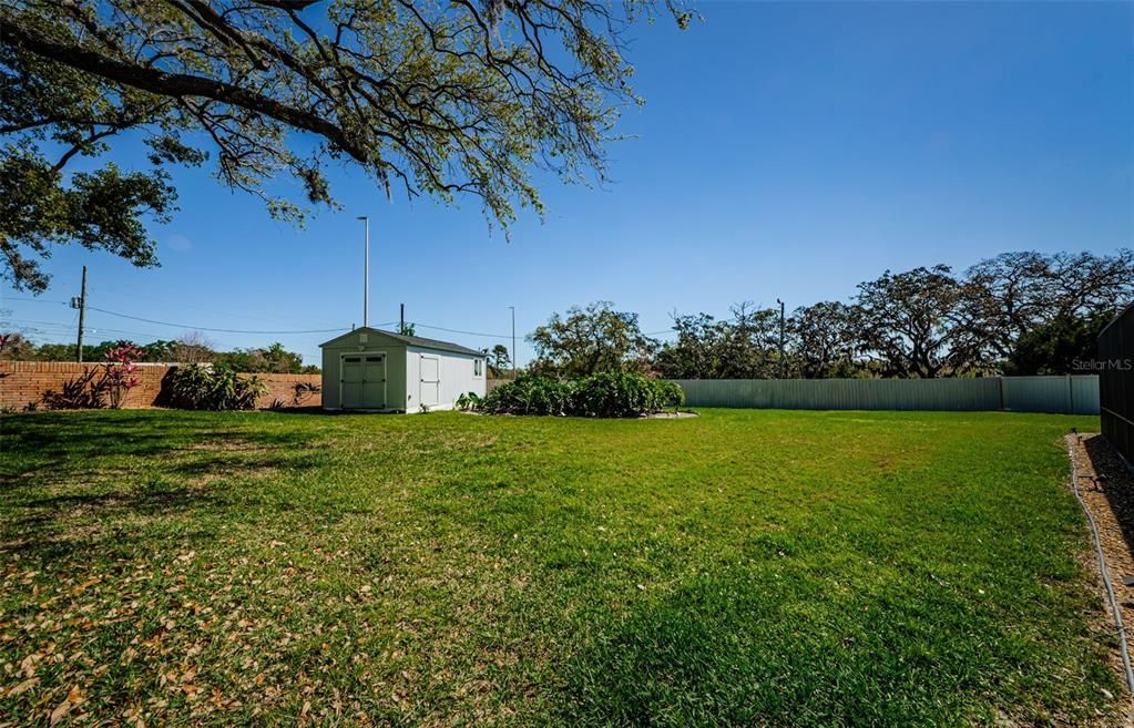 Back yard completely fenced showing large shed with office, wifi, electric, and air conditioning and separate storage area.