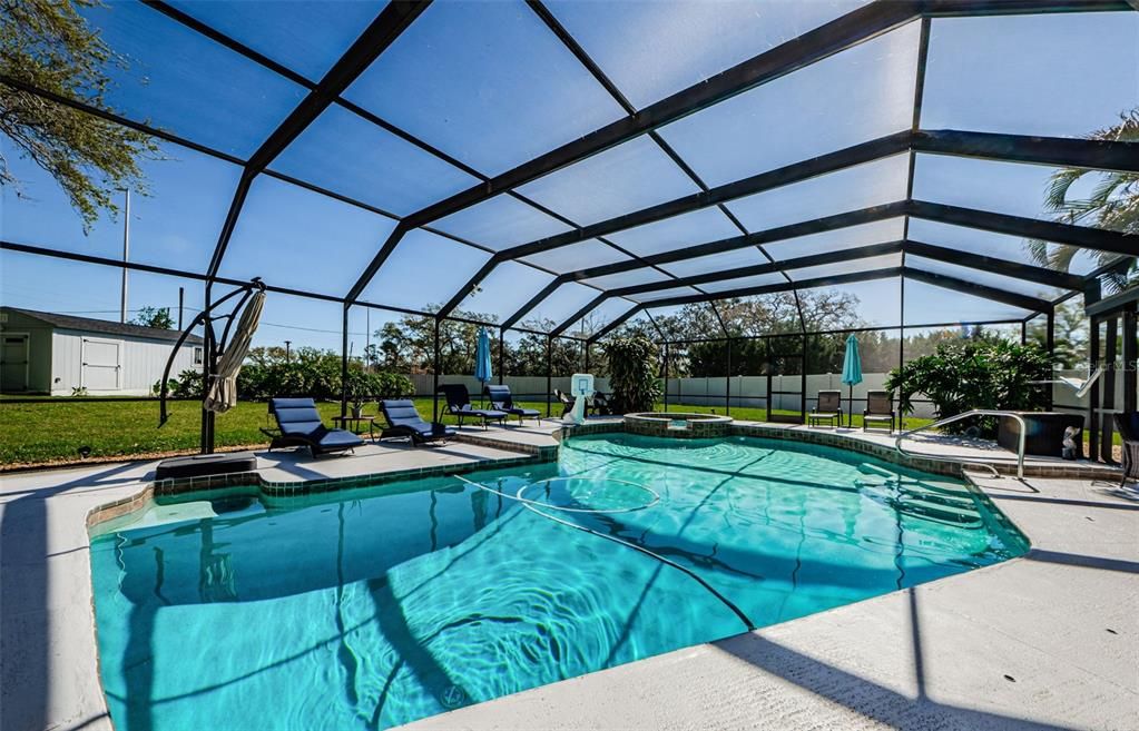 Sparkling heated pool and spa, caged with night time led lighting attached to overhead cage.