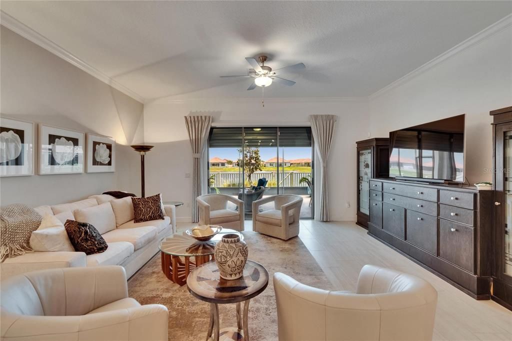 Living room looking through triple slider to lanai and pond.