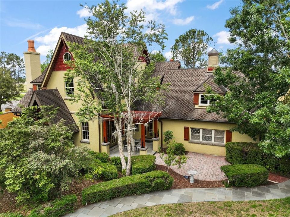 steeply pitched gable roof, prominent wood accents, warm stucco facade and stone walkway