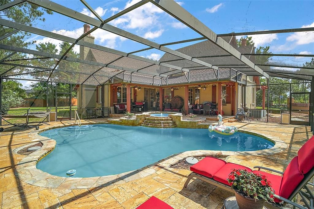 stone paver deck surrounds the free flow design of this pool with spa, edged with natural stone