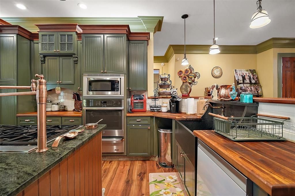 Large farm house sink, wood countertops, cooking island, cooper look cabinet hardware, beadboard cabinets with tons of custom millwork