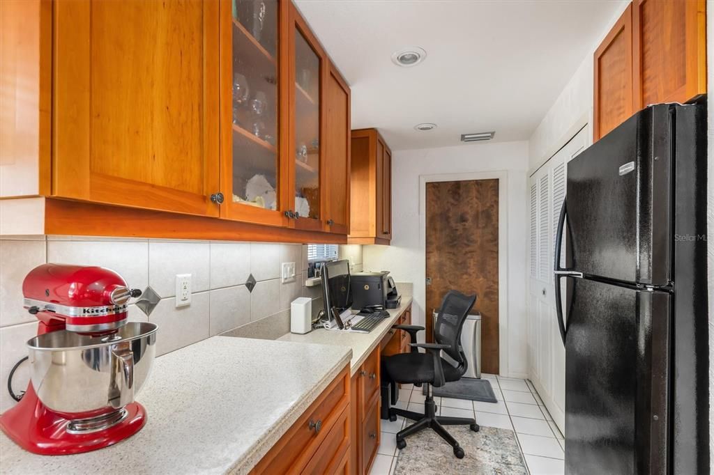 A desk area with pantry and second refrigerator