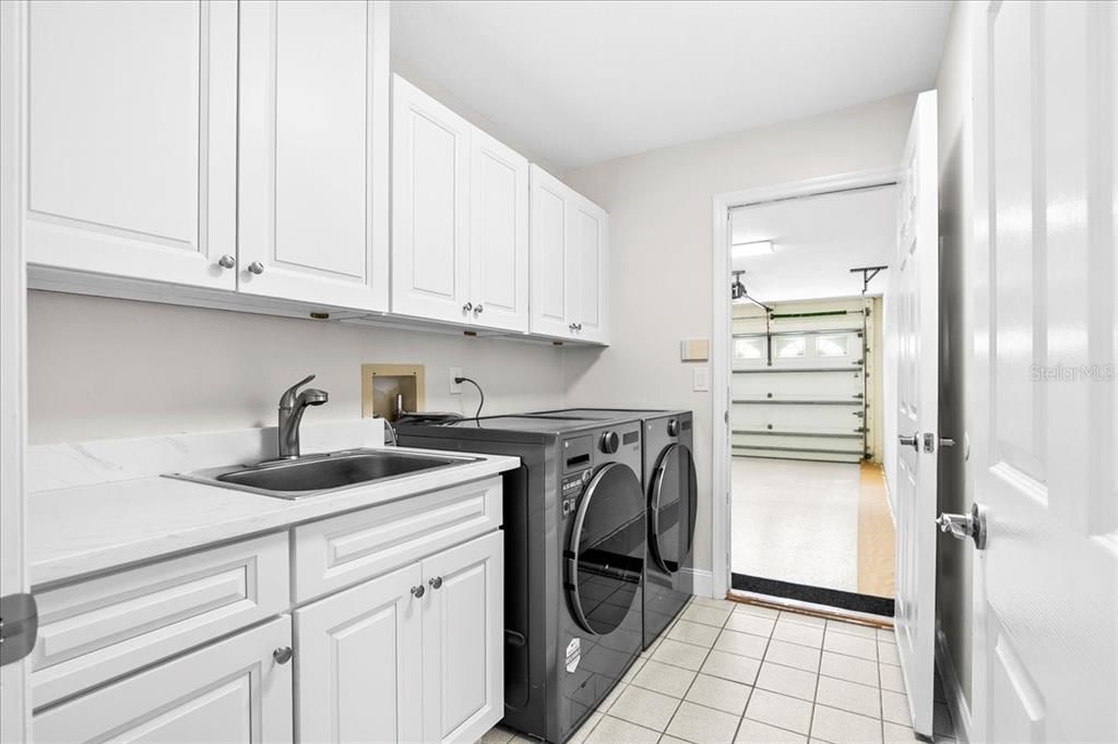 Large laundry room offers a utility sink, added storage and folding counter.