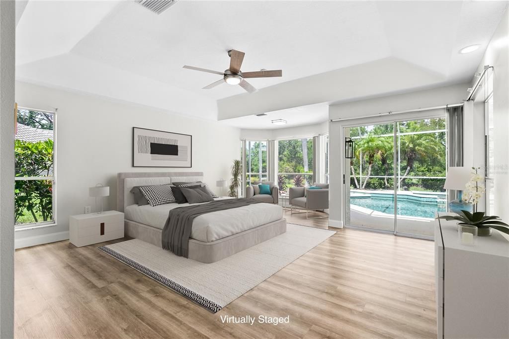 Primary bedroom suite with lounging area and direct access to the screened lanai. (Virtually Staged)