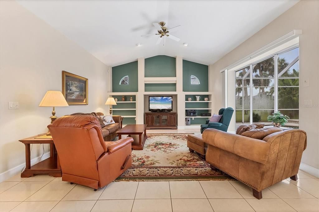 FAMILY ROOM VIEW FROM KITCHEN WITH BUILT INS ON BACK WALL AND ANOTHER TRIPLE SLIDER TO POOL AND LANAI