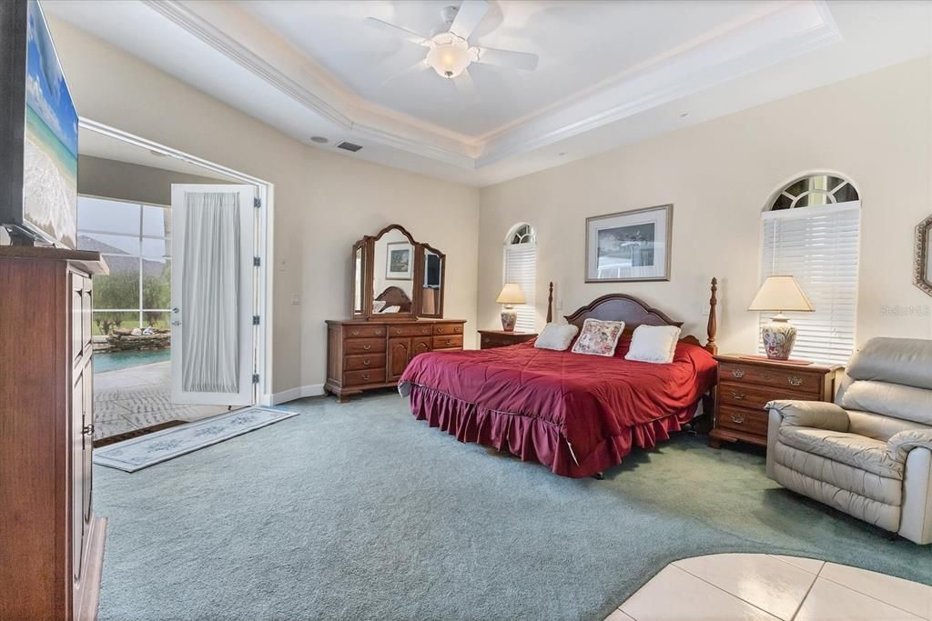 ALTERNATE VIEW OF PRIMARY BEDROOM WITH FRENCH DOORS OPEN TO POOL AND LANAI