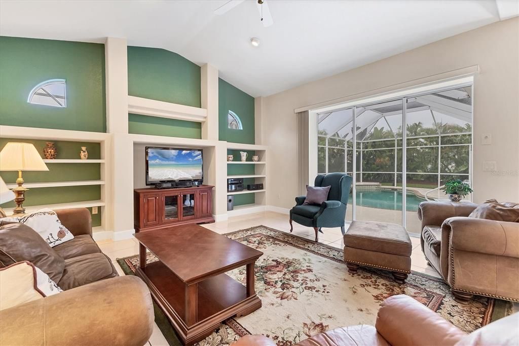 FAMILY ROOM CLOSE UP TO SHOW BUILT INS AND TRIPLE SLIDER SHOWING POOL OUTSIDE