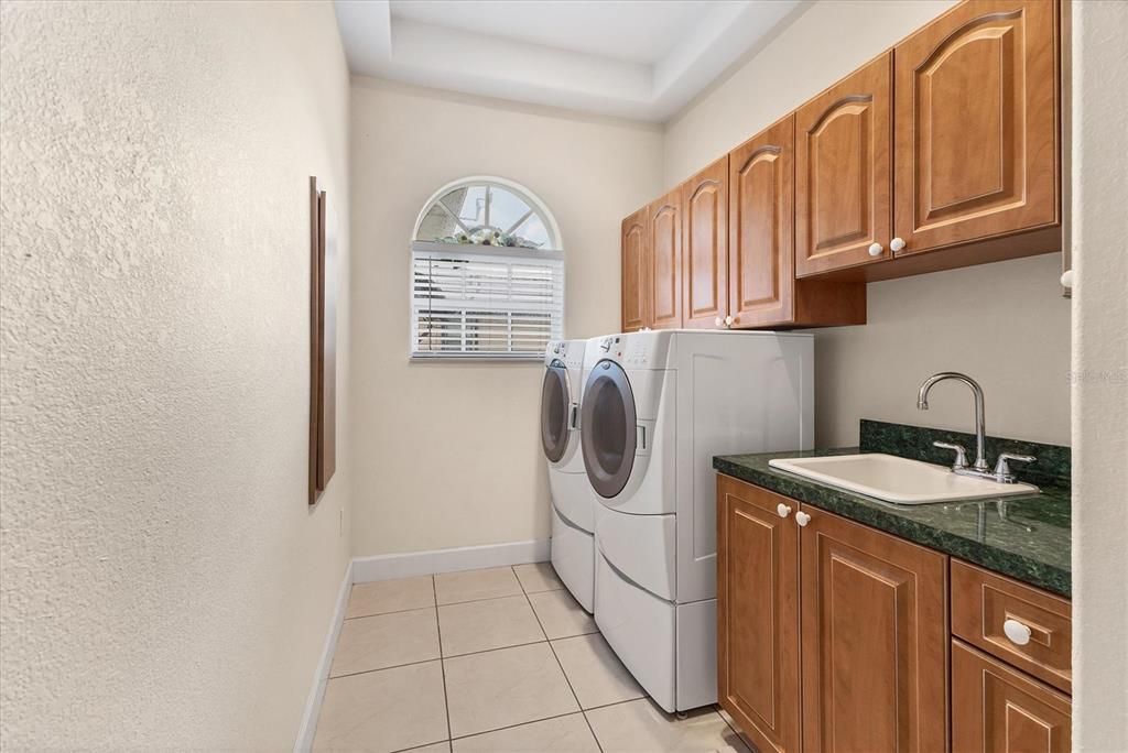 LAUNDRY ROOM WITH STORAGE AND UTILITY SINK AT END OF HALL TO KITCHEN