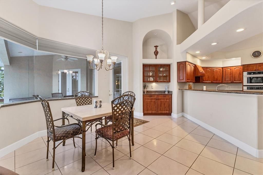 BREAKFAST NOOK AREA WITH AQUARIUM WINDOW AFFORDING VIEWS TO POOL AS WELL AS BUILT IN BUFFET WITH GLASS FRONT CABINETS
